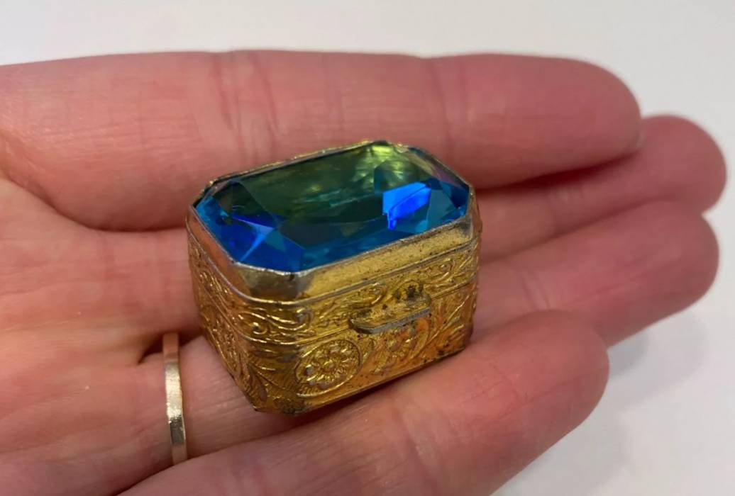 Pill box of gilded metal, with a large blue stone on the lid. Early 20th century. 