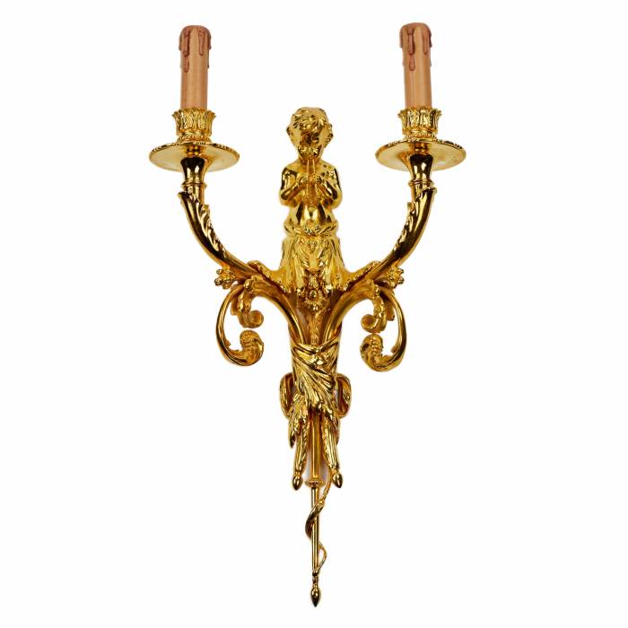 A pair of gilded sconces, with currency curls, surmounted by cherubs. 