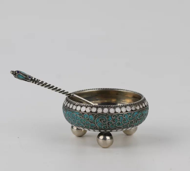 An elegant silver salt cellar with a spoon. 