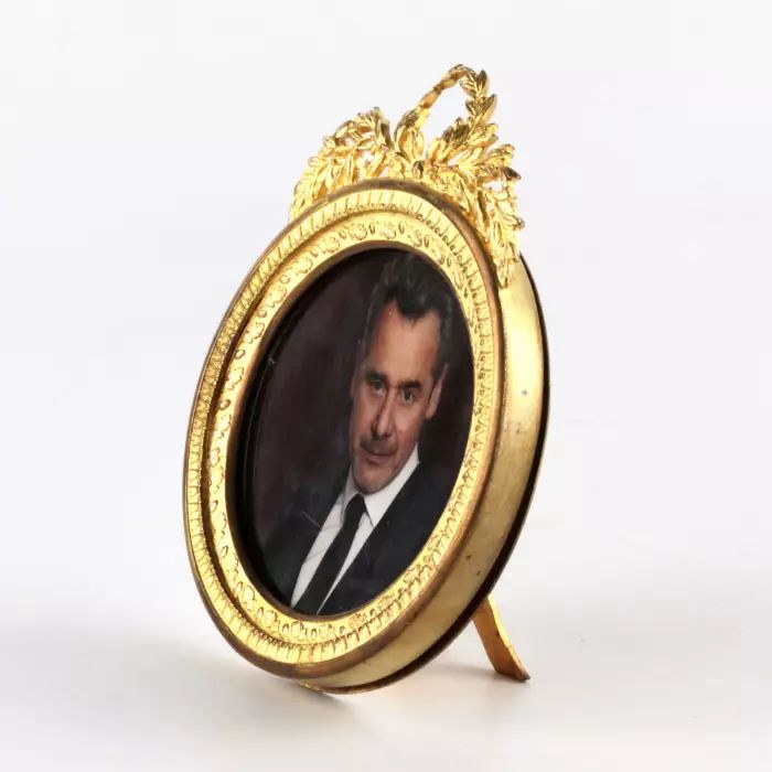 Round photo frame with empire decor. 