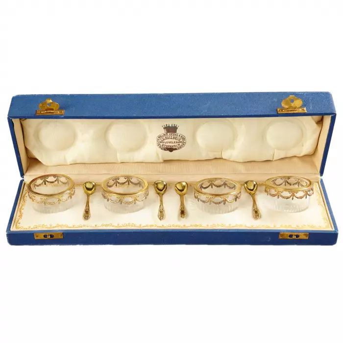 A set of four crystal saltcellars with spoons.