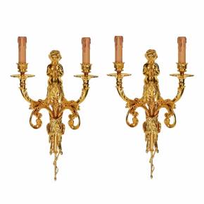 A pair of gilded sconces, with currency curls, surmounted by cherubs. 