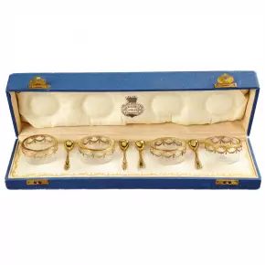 A set of four crystal saltcellars with spoons.